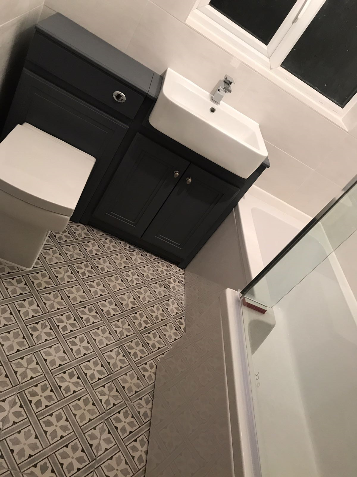 Completed kitchen refurbishment with quartz worktops in an Ilford terraced home — Compact bathroom with wall-hung vanity, WC and patterned floor tiling — bathroom fitting by RJS Innovative Building, East London
