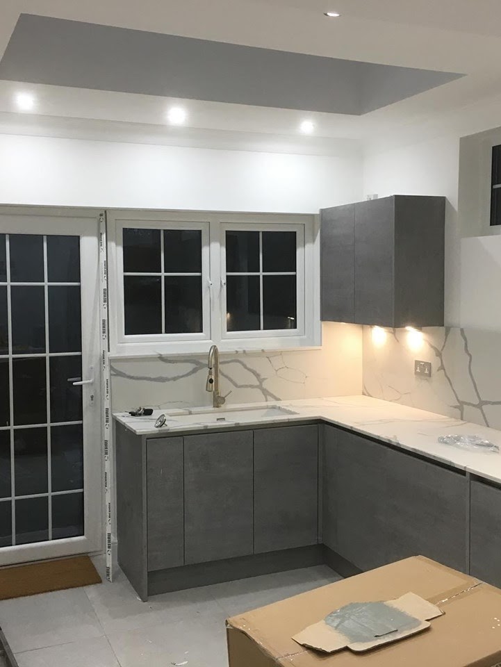 Kitchen Fitting & Refurbishment in Buckhurst Hill, IG9 — Handleless grey kitchen with marble-effect splashback panel mid-installation — kitchen fitting by RJS Innovative Building, East London