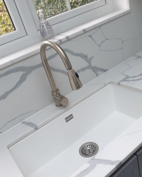 Completed kitchen refurbishment in a Stratford apartment with quartz worktops and integrated appliances — Calacatta-style white quartz worktop with undermounted sink and brushed mixer — worktop installation by RJS Innovative Building, East London