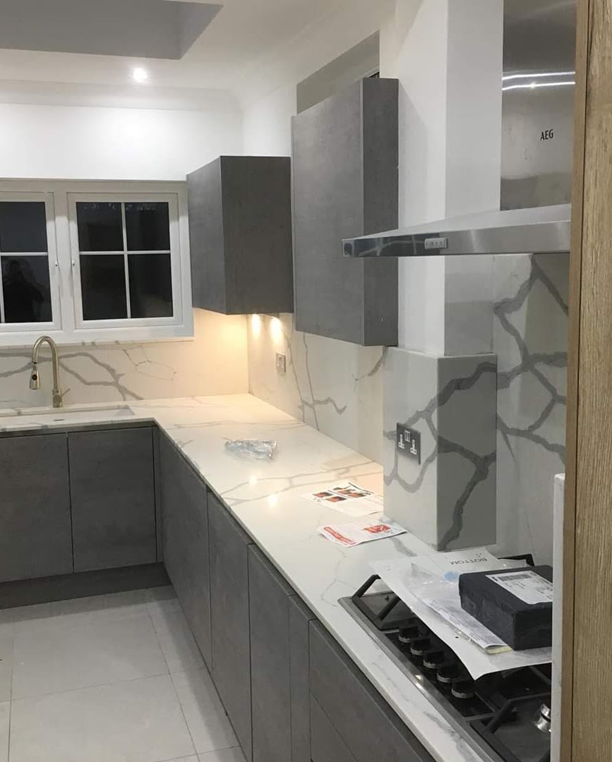 Completed hip-to-gable loft conversion on a 1930s Enfield semi-detached home — Handleless grey kitchen run with marble-effect quartz worktop and matching upstand — kitchen fitting by RJS Innovative Building, East London