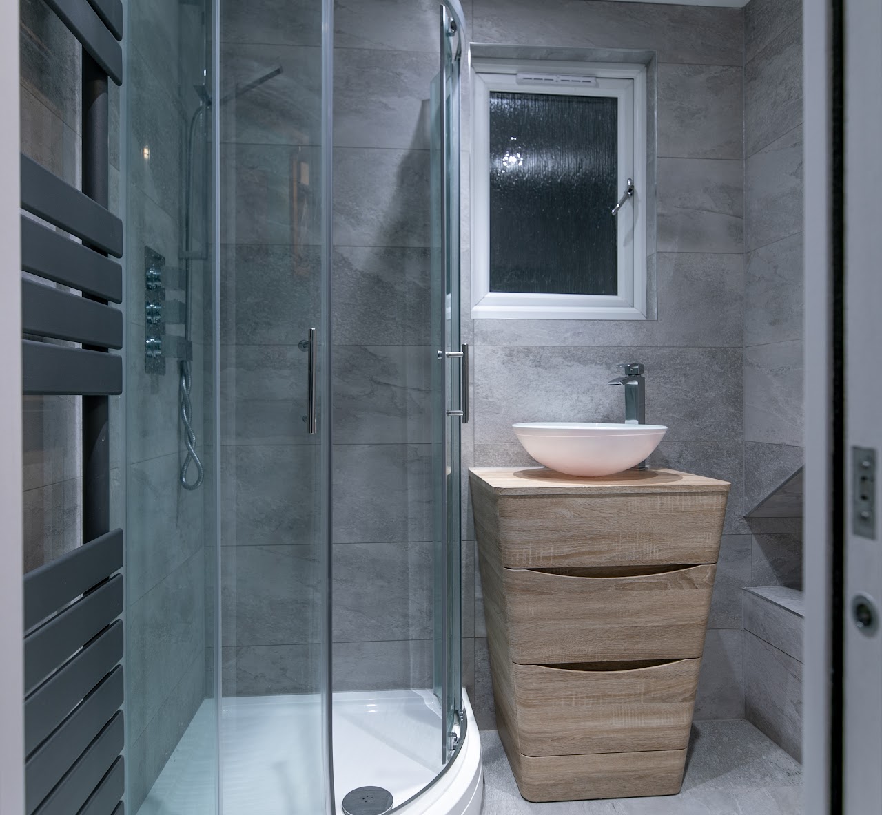 Compact ensuite shower room with quadrant enclosure, oak vanity and counter-top vessel basin — bathroom fitting by RJS Innovative Building, East London