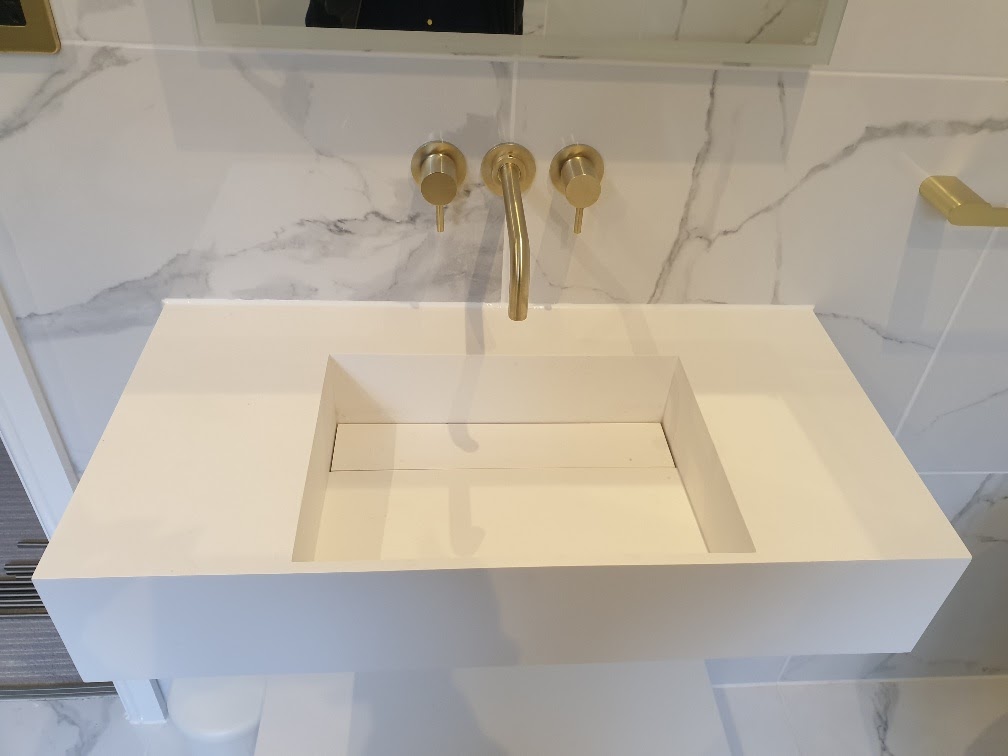 Floating white quartz vanity top with brushed-gold wall-mounted basin taps — worktop installation by RJS Innovative Building, East London