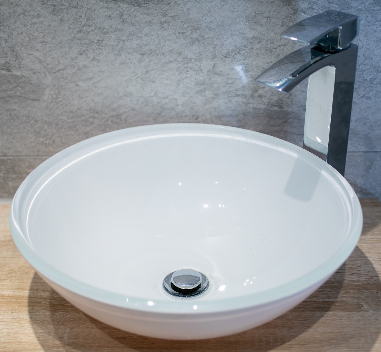 Granite, Marble & Quartz Worktops in Buckhurst Hill, IG9 — Counter-top vessel basin with chrome waterfall mixer on stone-effect surround — worktop installation by RJS Innovative Building, East London