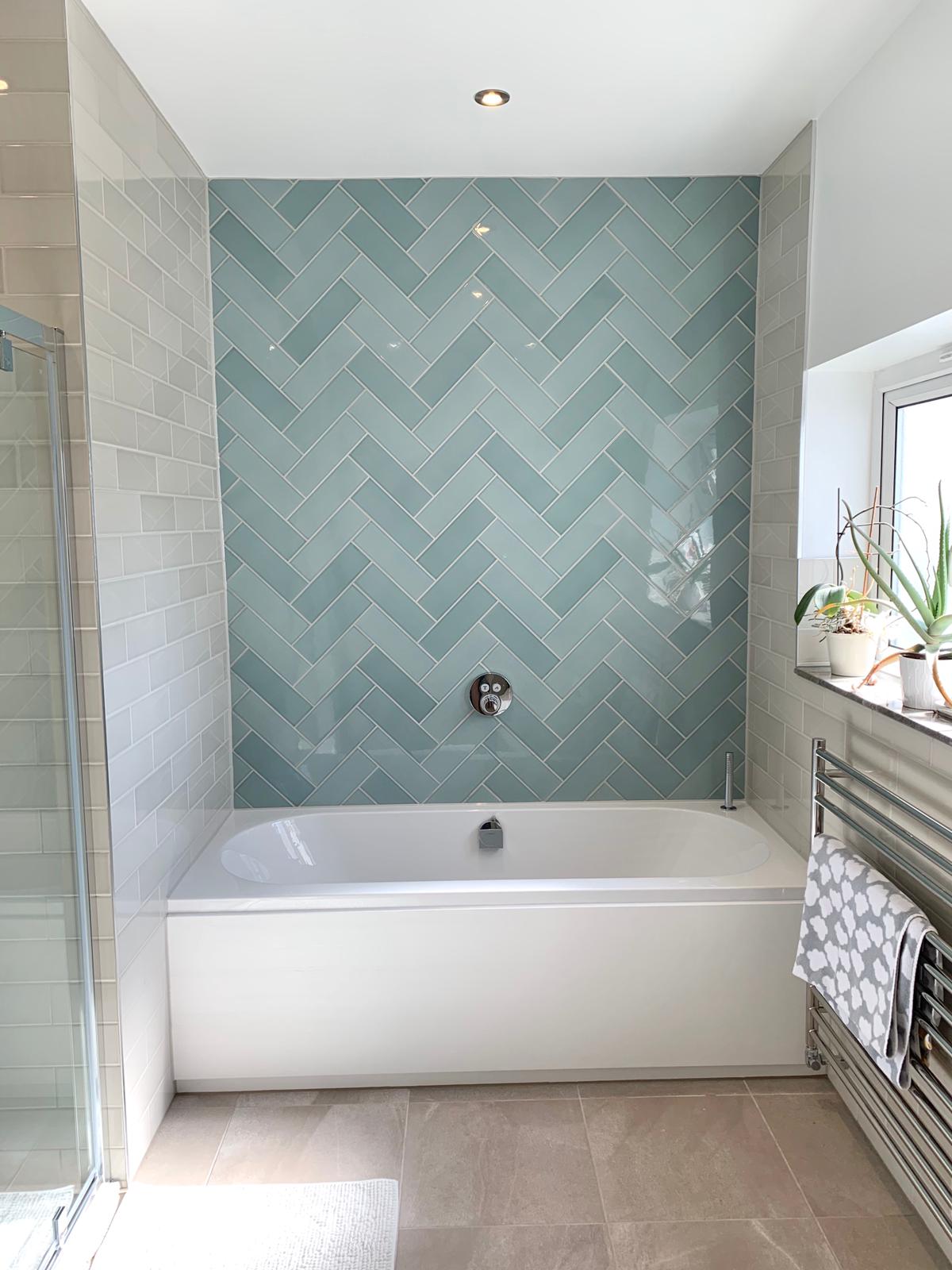 Sage-green herringbone wall tiling above a freshly tanked shower tray — tiling by RJS Innovative Building, East London