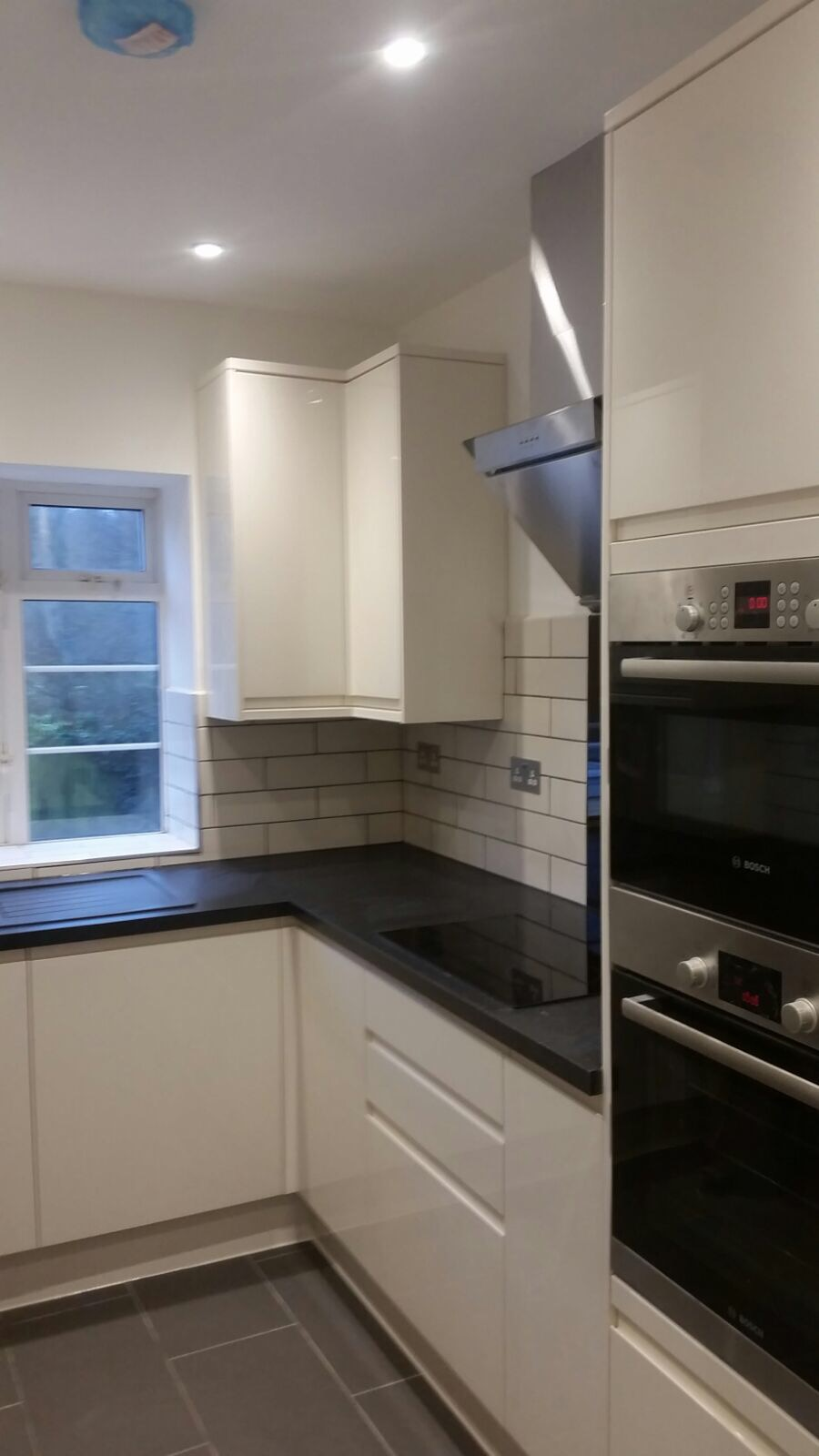 Kitchen fitter installing modern handleless wall cabinets during the install phase of a kitchen project