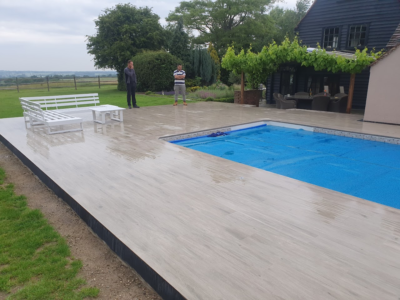 Residential Swimming Pool Construction in Wanstead, E11 — Residential swimming pool with cover and porcelain plank deck — swimming pool construction by RJS Innovative Building, East London