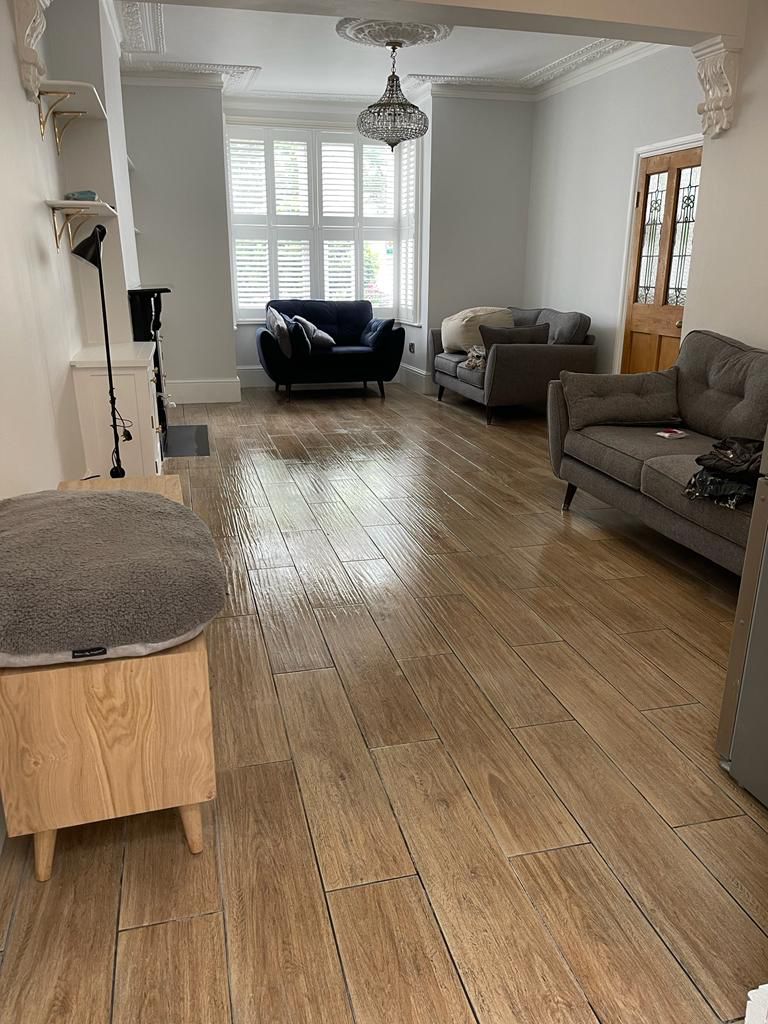 Completed L-shaped Victorian loft conversion with new master bedroom and ensuite in Wanstead — Through-lounge with restored ornate cornicing, crystal chandelier and wood-effect porcelain plank flooring — full house renovation by RJS Innovative Building, East London