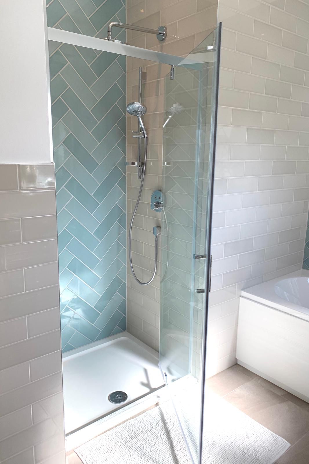 Completed full strip-back-to-brick renovation of a 1930s Loughton detached home — Walk-in shower with teal herringbone feature wall, cream metro tiling and chrome thermostatic shower — bathroom refurbishment by RJS Innovative Building, East London