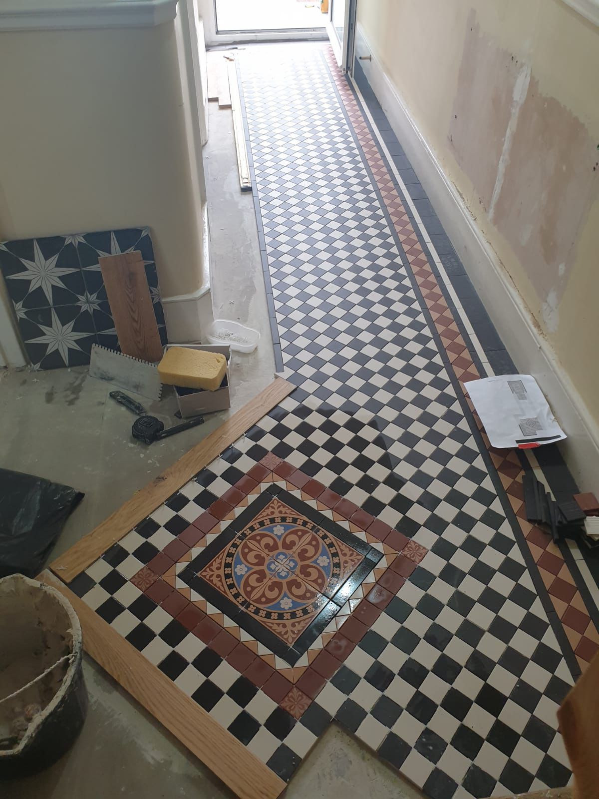Completed rear dormer loft conversion on a South Woodford Edwardian terrace by RJS Innovative Building — Restored Victorian geometric hallway floor tiling with patterned medallion border in progress — tiling by RJS Innovative Building, East London